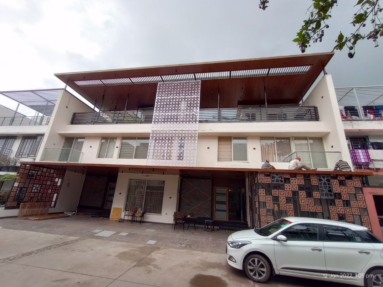 Modern residential building facade with a custom jaali screen and wood-clad canopy