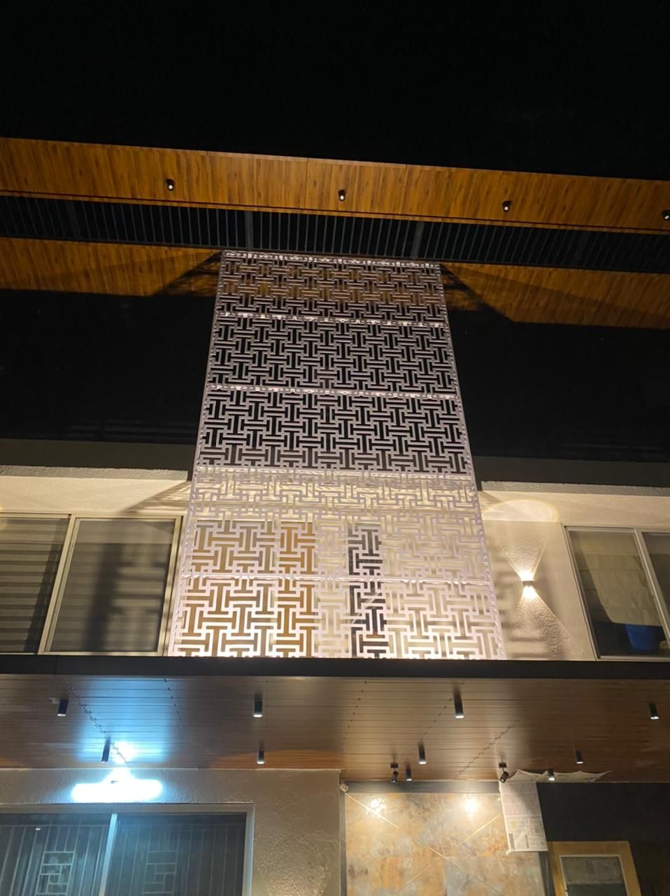 Backlit perforated metal partition screen on an outdoor terrace
