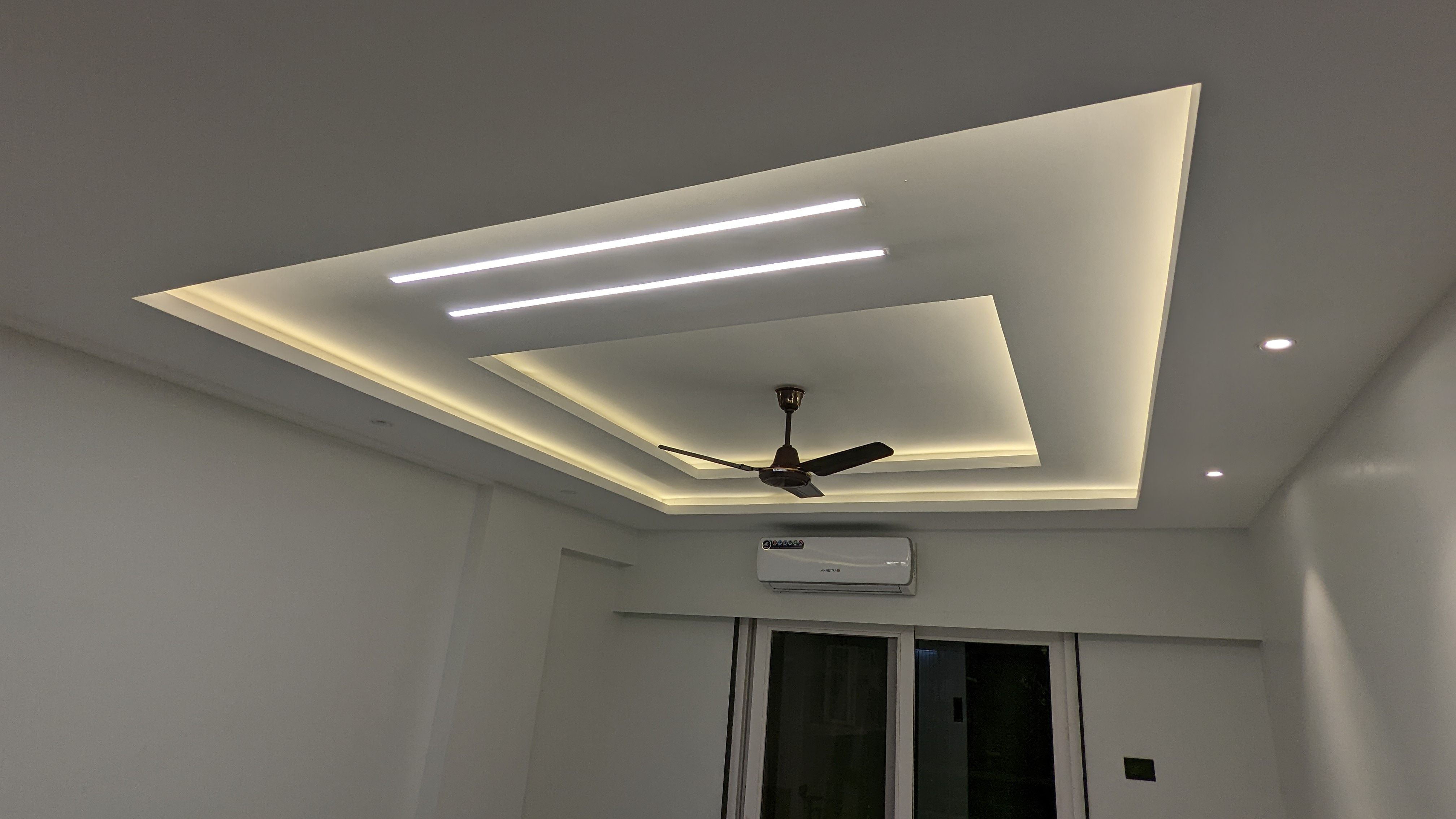 Layered false ceiling with cove lighting and a ceiling fan