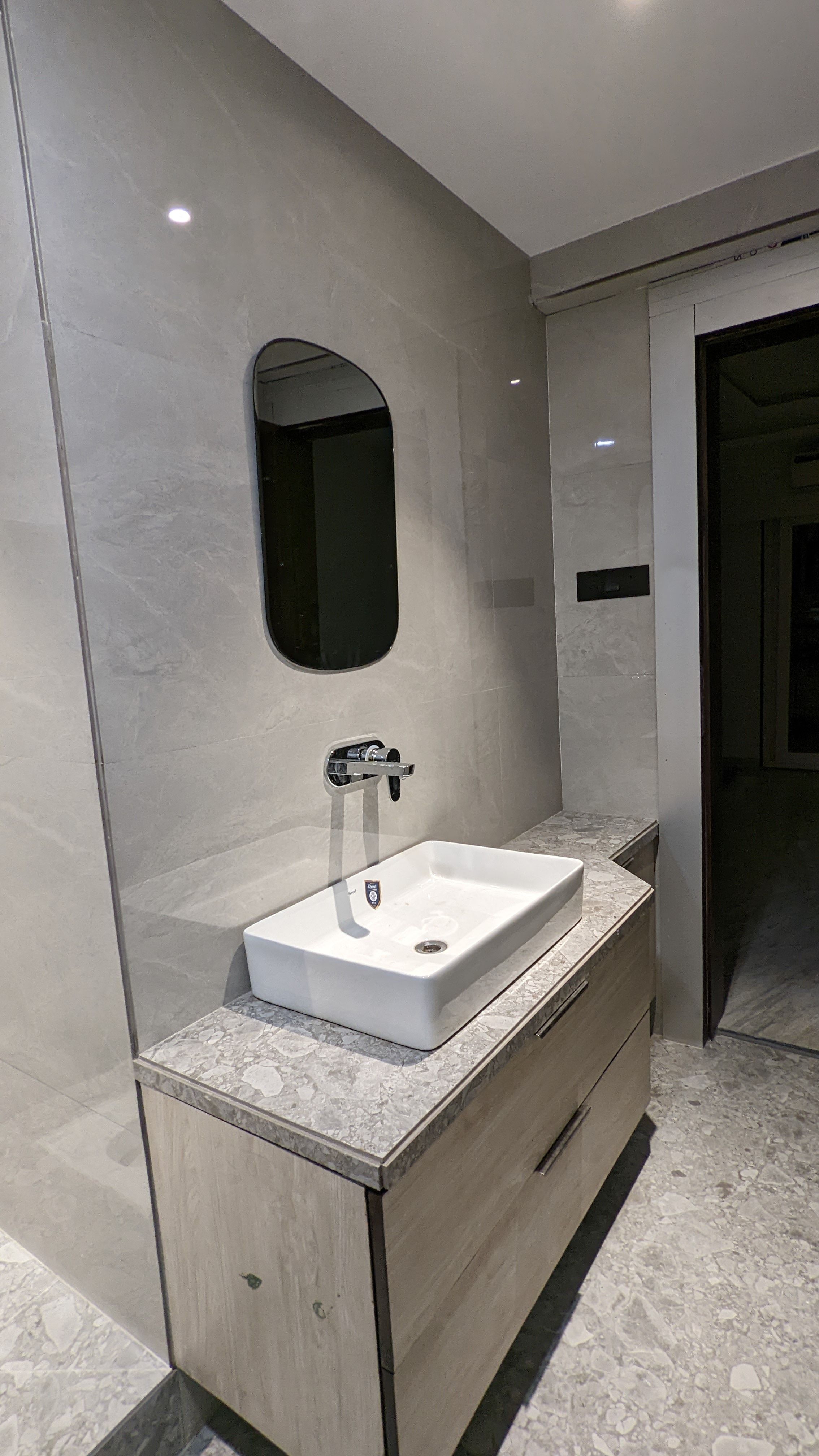 Bathroom vanity with a vessel sink, wall-mounted faucet and round mirror