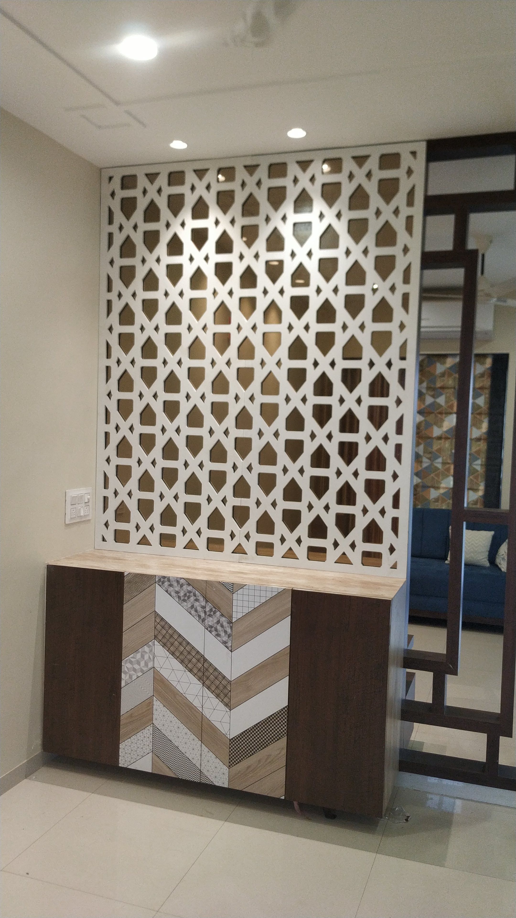 Foyer jaali partition wall above a chevron-pattern console unit