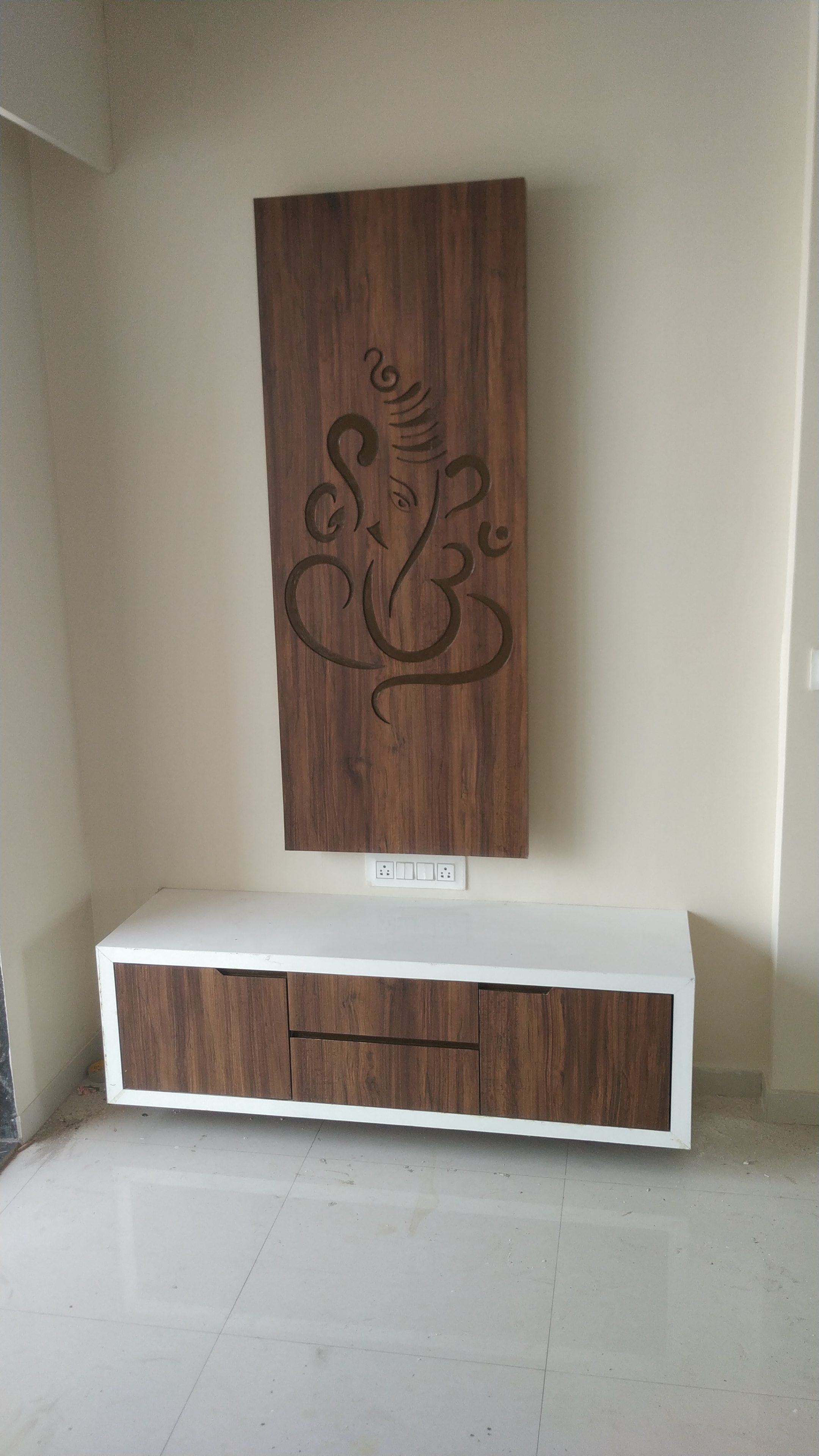 Hand-carved wooden Ganesh panel above a TV console