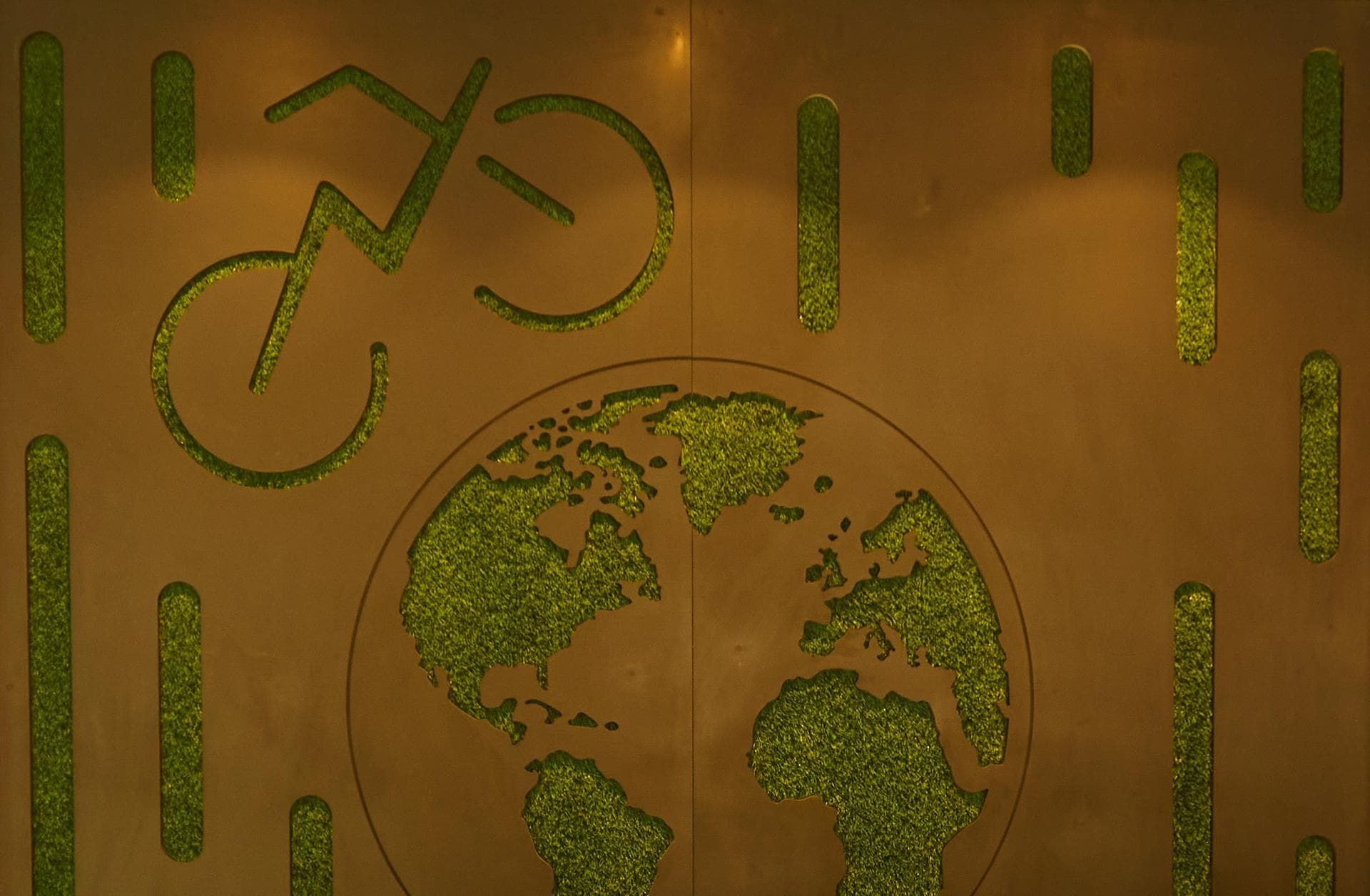 Laser-cut sustainability motif detail: a globe and bicycle in moss